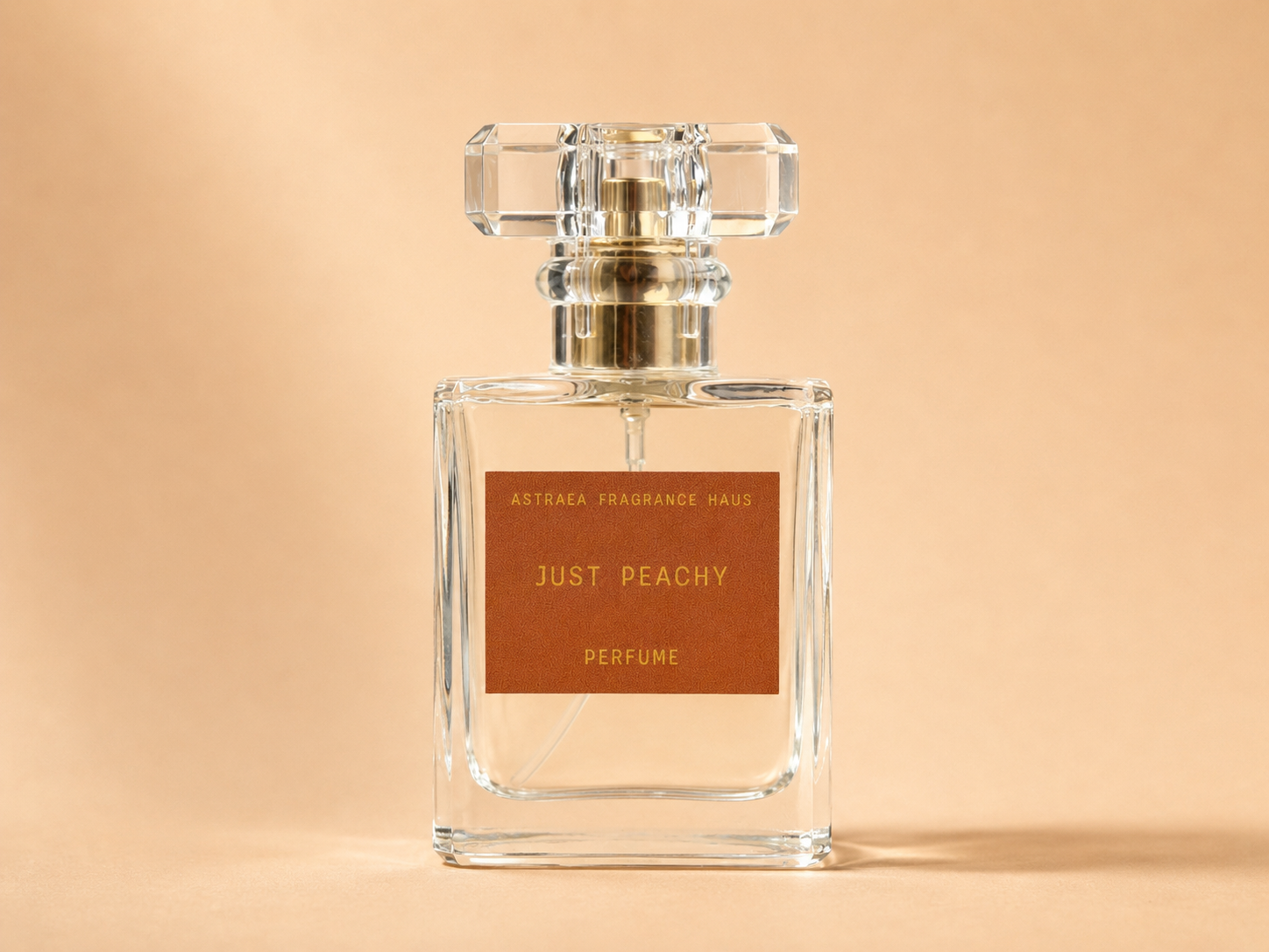 Astraea Fragrance Haus Just Peachy perfume bottle with peach and floral design on a white background.