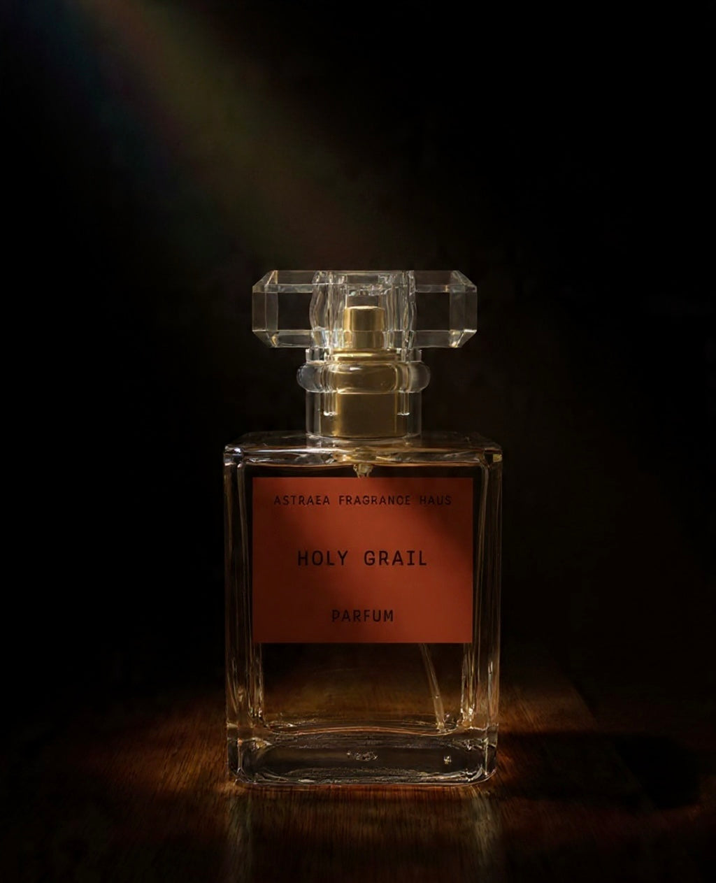 Astraea Fragrance Haus Holy Grail perfume bottle with elegant design and gold accents on a reflective surface.