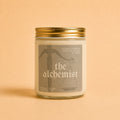 A bottle of Astraea Fragrance Haus "The Alchemist" perfume with a sleek glass design and minimalist label on a neutral background.