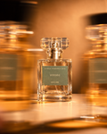 Voodoo perfume bottle by Astraea Fragrance Haus with a clear glass rectangular shape and decorative cap, blurred background with warm lighting.