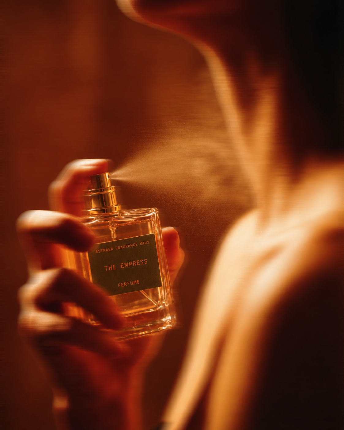 A woman holding a bottle of The Empress perfume by Astraea Fragrance Haus, elegant packaging with floral design.
