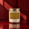 A bottle of Crimson & Fir fragrance by Astraea Fragrance Haus, featuring a sleek design with deep red and green accents.
